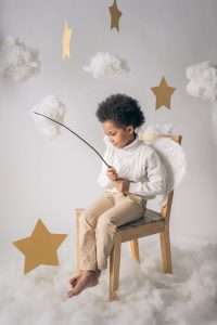 cute black boy in angel costume with wand with star