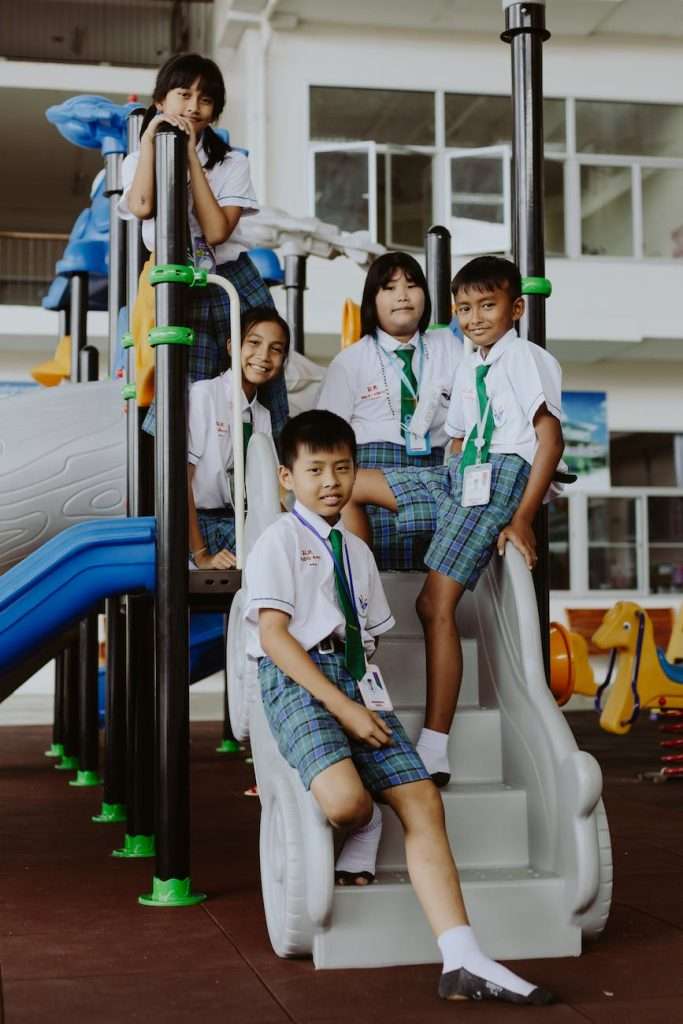 portrait of boys and girls in school uniforms sitting in school gymnasium